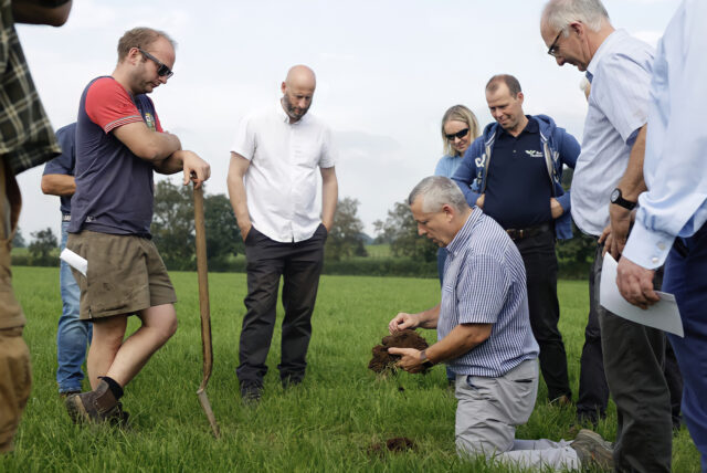 Five people gathered around man holding up soil