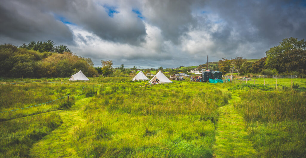 green field with three bell tents