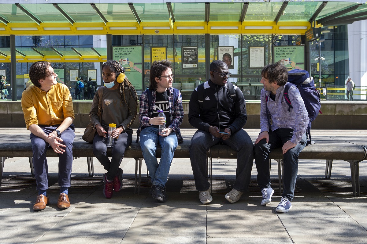 Young people and support workers discussing accessible transport at tram stop