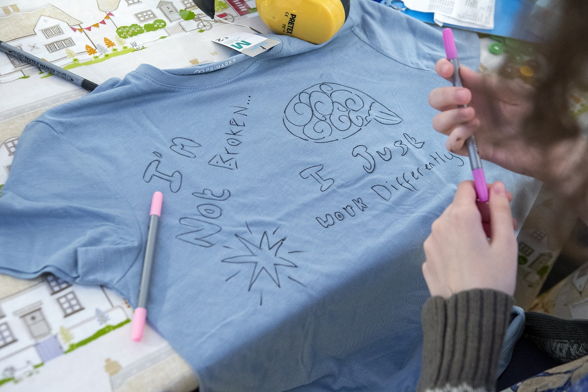 Young person illustrating t-shirt. It reads 'I'm not broken, I just work differently'