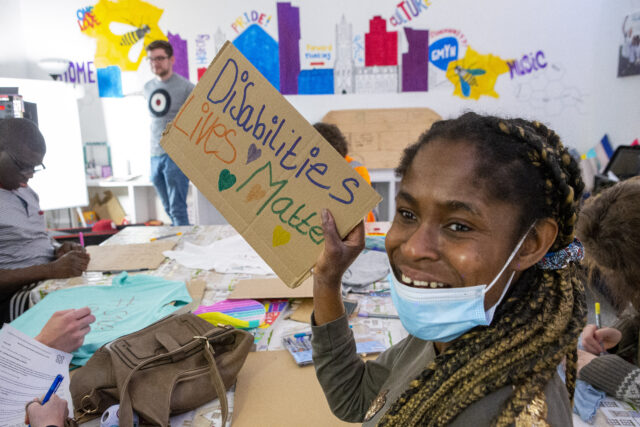 A young female activist holds up a sign saying 'disabilities lives matters' as part of an advocacy project in Manchester